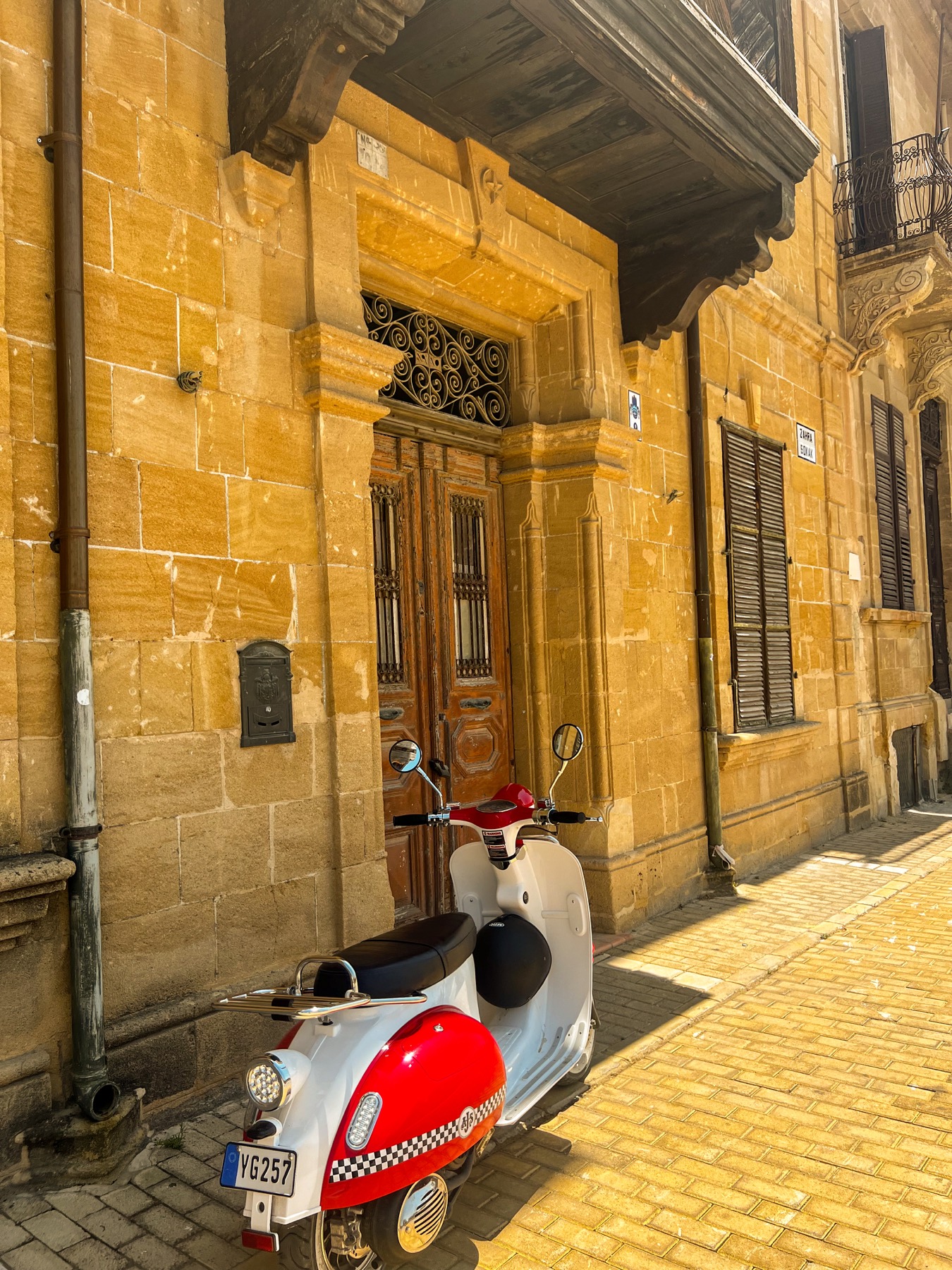 Red and white scooter in front of a warm stone building