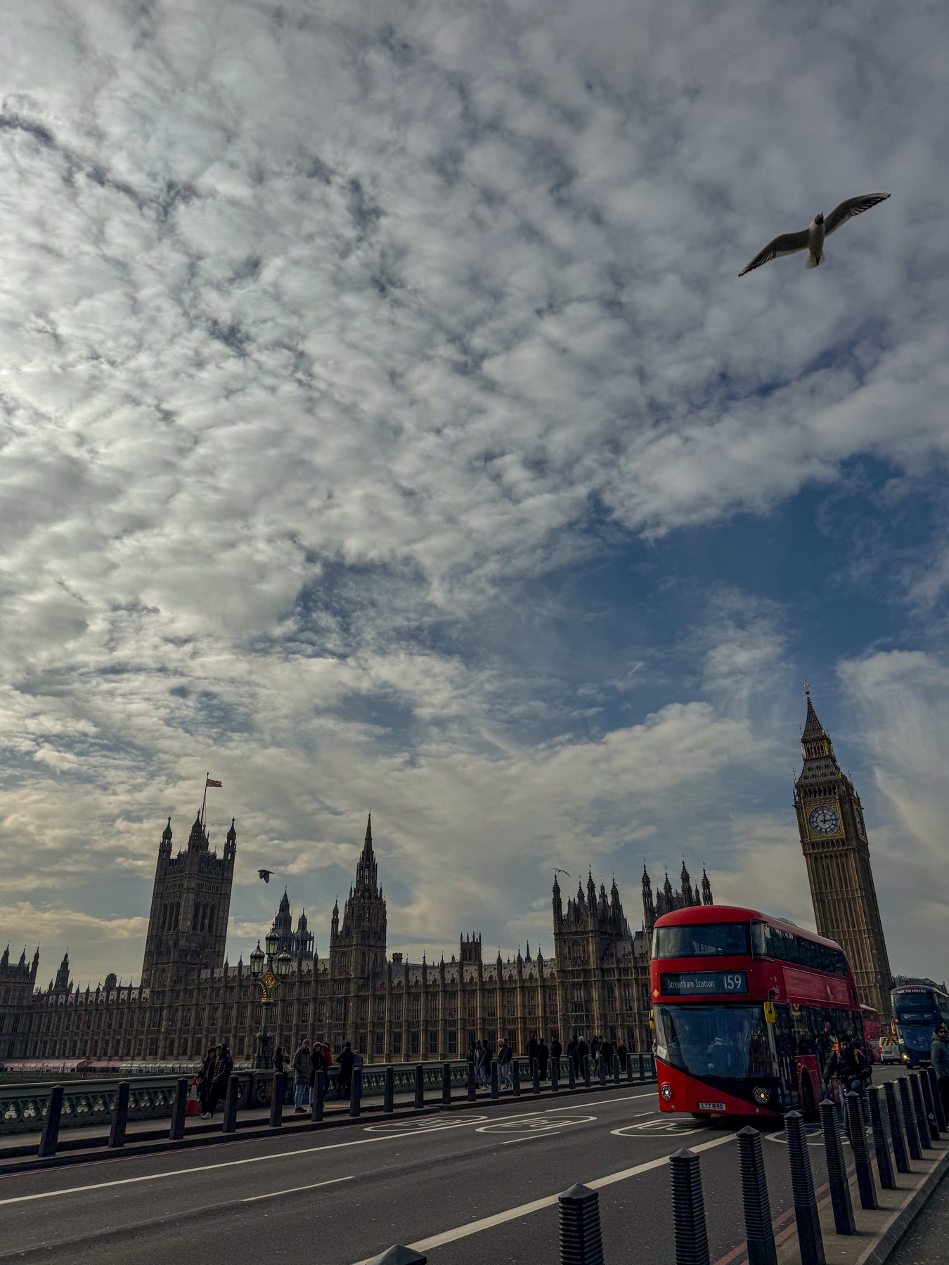 Westminster, Big Ben and a red double-decker bus beneath a cloudy sky
