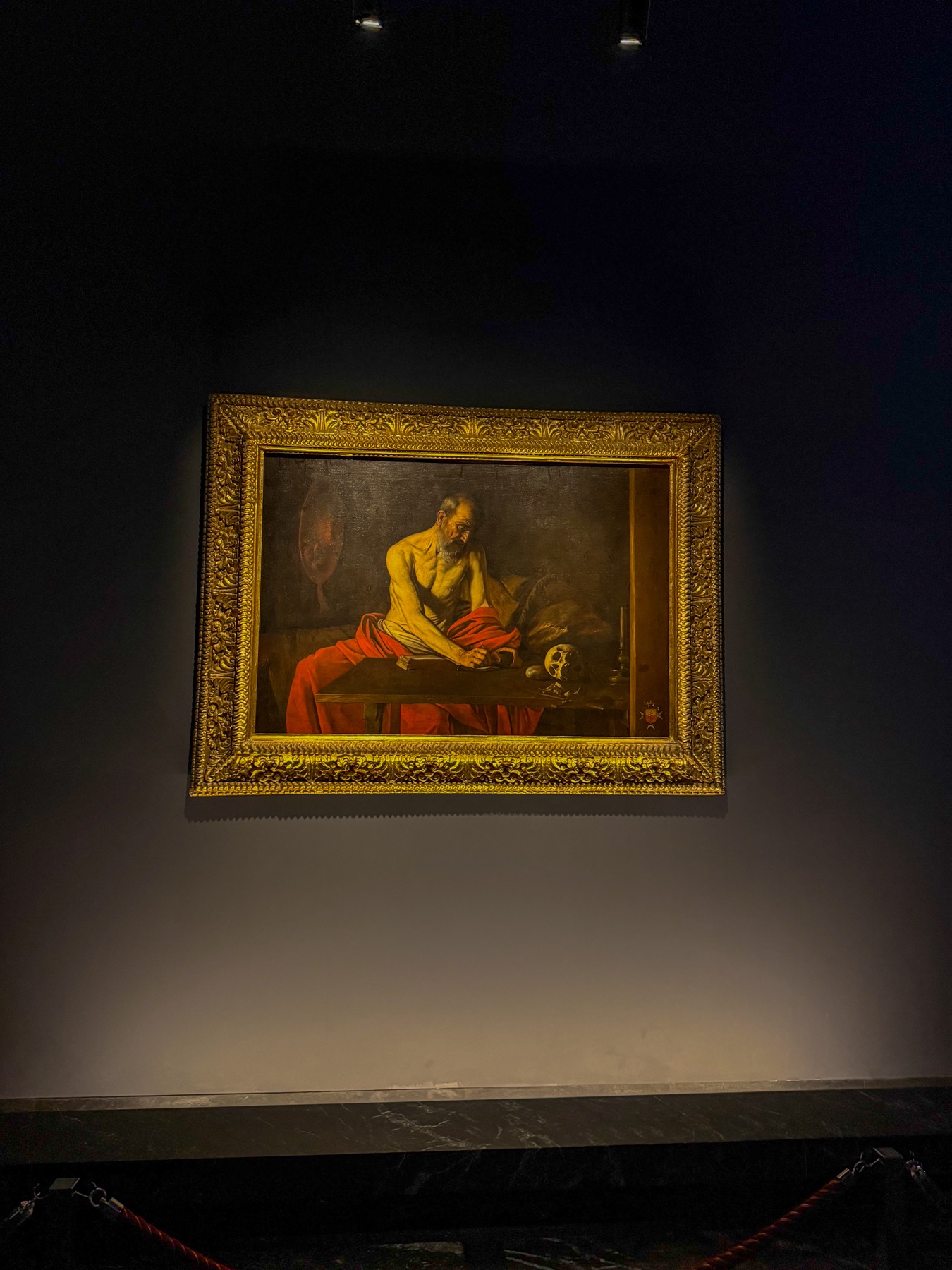 A dramatic old master painting displayed in a dark gallery