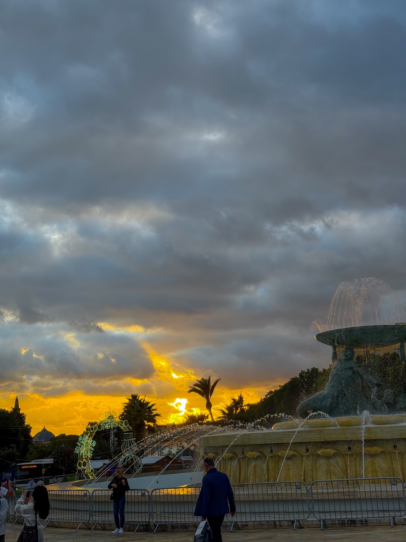 A fountain silhouetted against a dramatic Maltese sunset